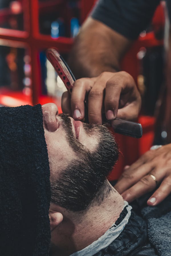 a customer's beards being shaved by the baber